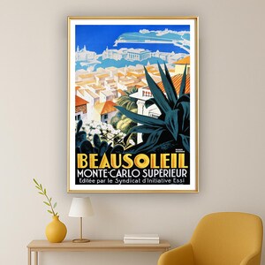 May include: A framed vintage travel poster for Beausoleil, Monte-Carlo Sup&eacute;rieur. The poster features a vibrant illustration of a coastal town with orange rooftops, blue sky, and dark green plants. The text is in yellow and black.