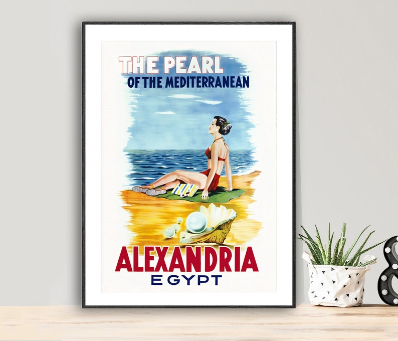 K&ouml;nnte beinhalten: Vintage-Reiseposter, das Alexandria in &Auml;gypten als "Die Perle des Mittelmeers" bewirbt. Das Poster zeigt eine Frau in einem roten Badeanzug, die sich an einem Strand mit einer gro&szlig;en Perle in einer Muschel entspannt.