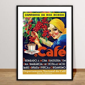 May include: Framed vintage poster advertising coffee. The poster shows a woman in a yellow headscarf picking red coffee cherries. Text includes "Campanha da Boa Bebida" and "Cafe". The poster is in a black frame.