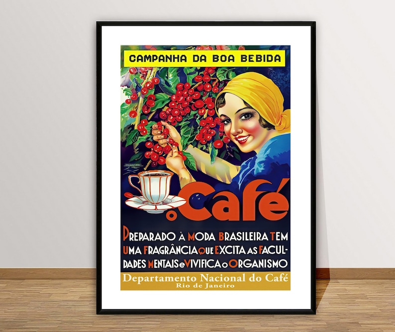 May include: Framed vintage poster advertising coffee. The poster shows a woman in a yellow headscarf picking red coffee cherries. Text includes "Campanha da Boa Bebida" and "Cafe". The poster is in a black frame.