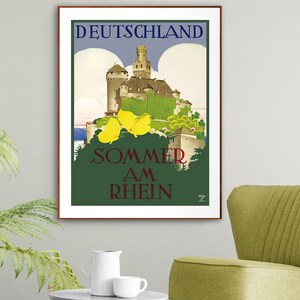 May include: A vintage travel poster advertising summer vacations in Germany. The poster features a picturesque castle nestled in a lush green landscape with a blue sky and fluffy white clouds. The text on the poster reads "DEUTSCHLAND SOMMER AM RHEIN".