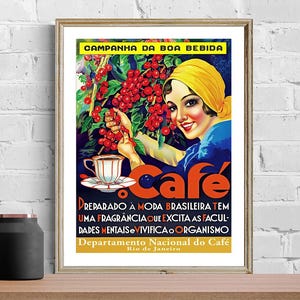 May include: Framed vintage poster advertising coffee. The artwork shows a woman in a yellow headscarf picking red coffee cherries. The poster includes the word "cafe" and text in Portuguese. The poster is in a gold frame.