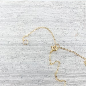 May include: A gold chain necklace with a lobster clasp closure. The chain is made of small, round links.