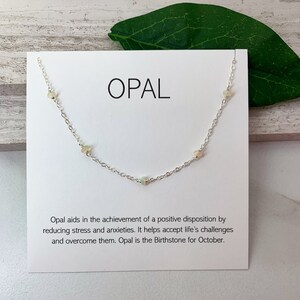 May include: A silver chain necklace with small opal stones. The card reads "OPAL" and includes information about the stone's meaning and birthstone status.