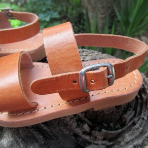 K&ouml;nnte beinhalten: Braune Ledersandalen mit Schnallenverschluss. Die Sandalen haben ein schlichtes Design und sind aus hochwertigem Leder gefertigt.