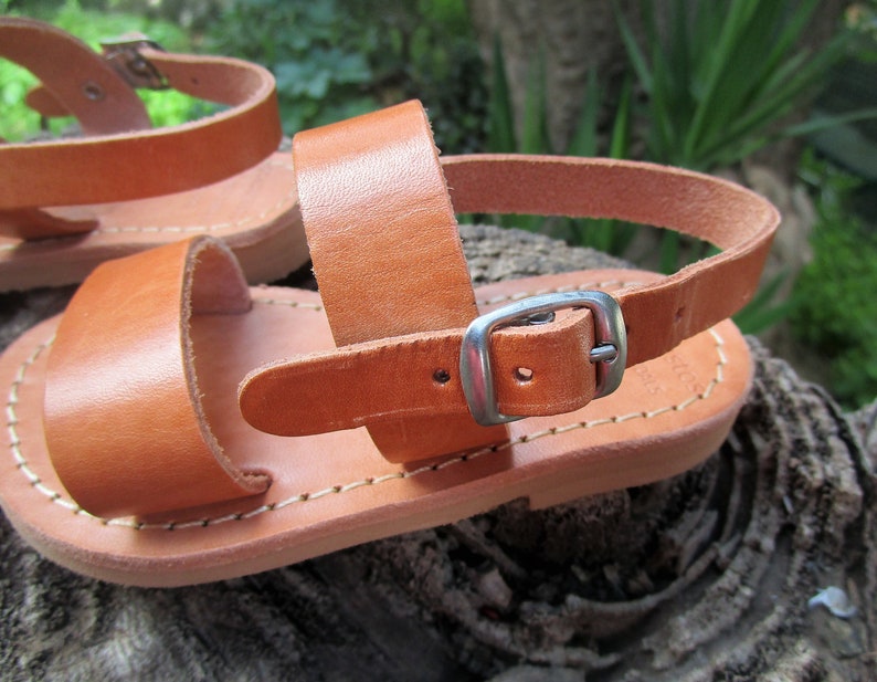 K&ouml;nnte beinhalten: Braune Ledersandalen mit Schnallenverschluss. Die Sandalen haben ein schlichtes Design und sind aus hochwertigem Leder gefertigt.