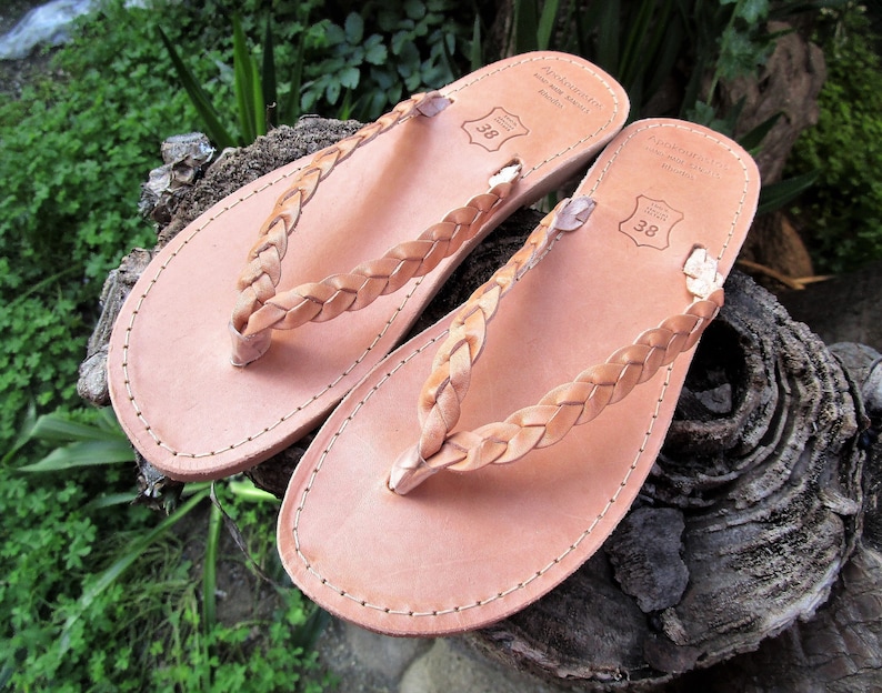 Pu&ograve; includere: Un paio di sandali in pelle color cuoio con cinturini intrecciati. I sandali hanno un design semplice e sono realizzati in pelle di alta qualit&agrave;.