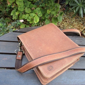 May include: A brown leather crossbody bag with a dark brown strap and a small brown logo on the front.