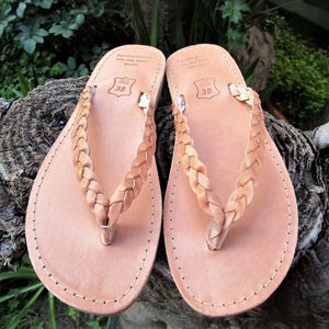 Pu&ograve; includere: Un paio di sandali in pelle color cuoio con cinturini intrecciati. I sandali hanno un design semplice e sono realizzati in pelle di alta qualit&agrave;. I sandali sono taglia 38.