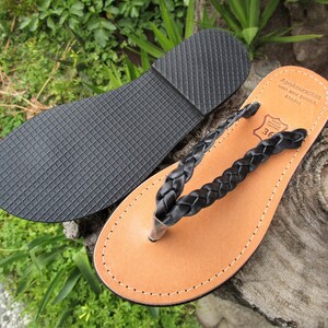 Pu&ograve; includere: Sandali a listino in pelle intrecciata nera con suola in pelle marrone. I sandali hanno una suola in gomma ed sono etichettati "Apokoronastos Hand Made Sandals Rhodes 36".