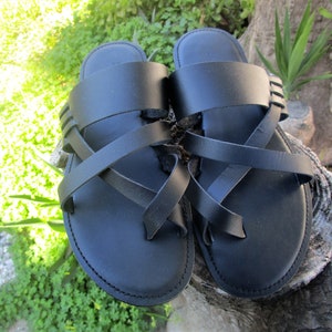 May include: A pair of black leather sandals with criss-cross straps. The sandals have a simple design and are perfect for warm weather.