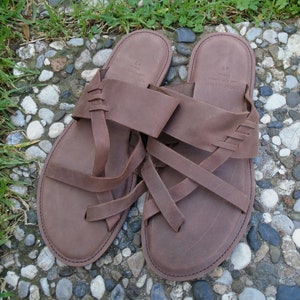 May include: A pair of brown leather sandals with multiple straps. The sandals have a simple design and are made of a high-quality material.