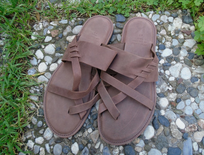 May include: A pair of brown leather sandals with multiple straps. The sandals have a simple design and are made of a high-quality material.