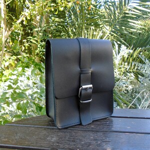 May include: A black leather messenger bag with a silver buckle closure.