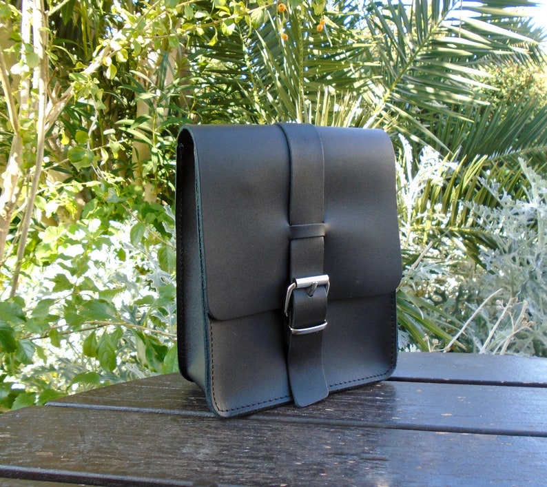 May include: A black leather messenger bag with a silver buckle closure.