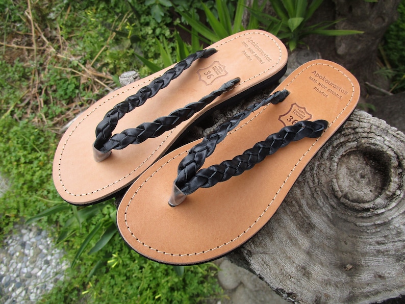 Pu&ograve; includere: Due paia di sandali in pelle nera con cinturini intrecciati. I sandali sono realizzati a Rodi, in Grecia. I sandali sono taglia 36.