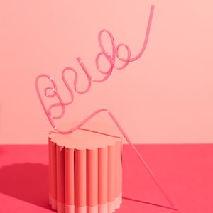 Image shows a pink straw in the shape of the word "Bride"
