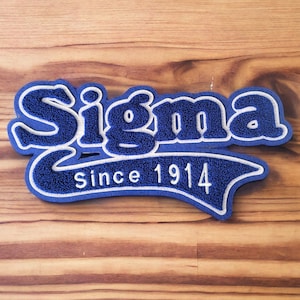 May include: Blue and white embroidered patch with the word "Sigma" and the text "Since 1914" in a white outline.