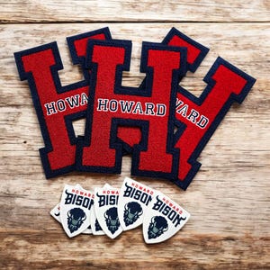 May include: A collection of red and navy blue embroidered patches. The patches feature the letter "H" with "HOWARD" in white text. Below are several white shield-shaped patches with a bison graphic and "HOWARD BISON" text.