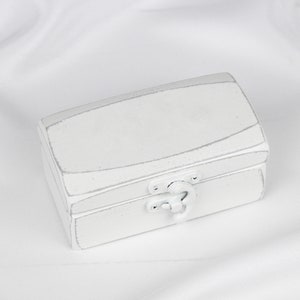 May include: A white wooden box with a hinged lid and a silver latch. The box has a distressed finish, giving it a vintage look.