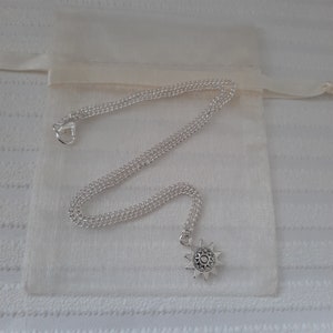 May include: A silver chain necklace with a silver star pendant. The star has a detailed design and is hanging from a silver chain.