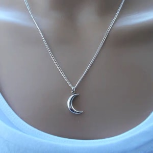 May include: A silver chain necklace with a crescent moon pendant.