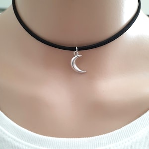 May include: A black choker necklace with a silver crescent moon pendant.
