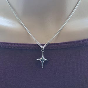 A simple silver coloured star charm hangs from a silver plated fine curb chain necklace. The necklace is available in several different lengths and is finished with a lobster clasp. Supplied in an organza gift bag ready to gift to someone special.