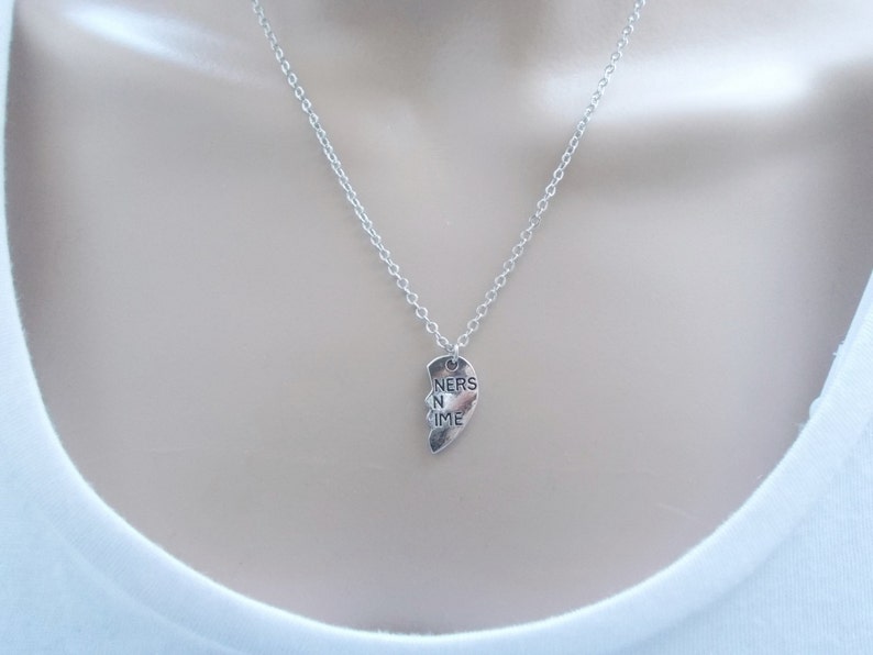 May include: A silver necklace with a heart-shaped pendant that says "Friends in Time".
