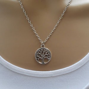 May include: A silver chain necklace with a circular pendant featuring a tree of life design.