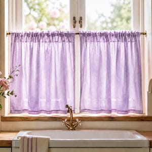 May include: A pair of light purple cafe curtains made of a semi-sheer fabric, featuring a gathered rod pocket top. The curtains are hung on a thin brass rod across a window, providing a soft, translucent filter for natural light in a kitchen.