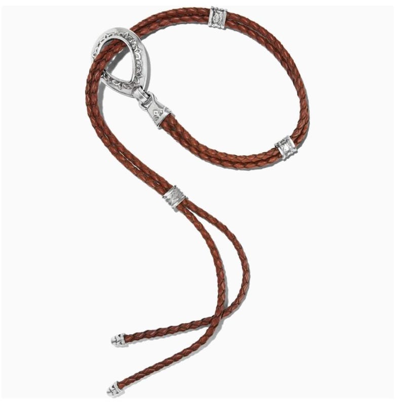 May include: A brown leather bolo tie with a silver clasp and accents. The braided leather cord forms a loop and two strands that end with decorative silver tips. The clasp has an oval shape with intricate detailing.