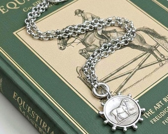 Peut inclure: Un collier argenté doté d'un pendentif circulaire avec un relief de cheval et un bord en forme de rayons de soleil. Le pendentif est fixé à une chaîne épaisse et texturée à maillons ronds avec un fermoir à bascule, formant un bijou métallique.