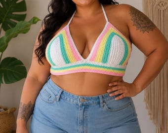 Può includere: Un top all'americana all'uncinetto con strisce orizzontali bianche, gialle, verde acqua e rosa, abbinato a pantaloncini di jeans azzurri con orlo sfrangiato. Il top ha una silhouette triangolare con sottili spalline da annodare al collo.