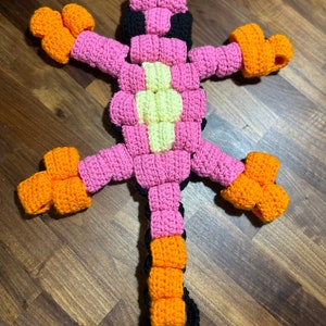 May include: A crocheted pink, orange and black lizard toy with a long tail.