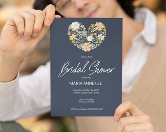 Op de afbeelding: Een blauwe uitnodiging voor een bruidsdouche met een bloemig hartontwerp. De uitnodiging luidt: "Join us for a Bridal Shower honoring Maria Anne Lee. Saturday, October 22, 2023, 3PM at Cheesecake Factory, 764 N. Anaheim, Irvine, CA 95478. RSVP to Michelle at (714) 678-4567."