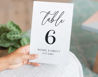 May include: White table number card with black calligraphy that says "Table 6" and the text "MICHAEL & CHRISTY 11.17.2021" and the website "DROOANDAYA.COM".