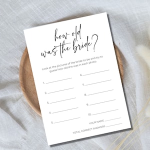 Peut inclure: Un jeu de douche nuptiale imprimable avec le texte "how old was the bride?" et des instructions pour deviner l'âge de la mariée sur chaque photo. Le jeu comprend 10 lignes vierges pour les réponses et un espace pour le nom du joueur et le nombre total de réponses correctes.