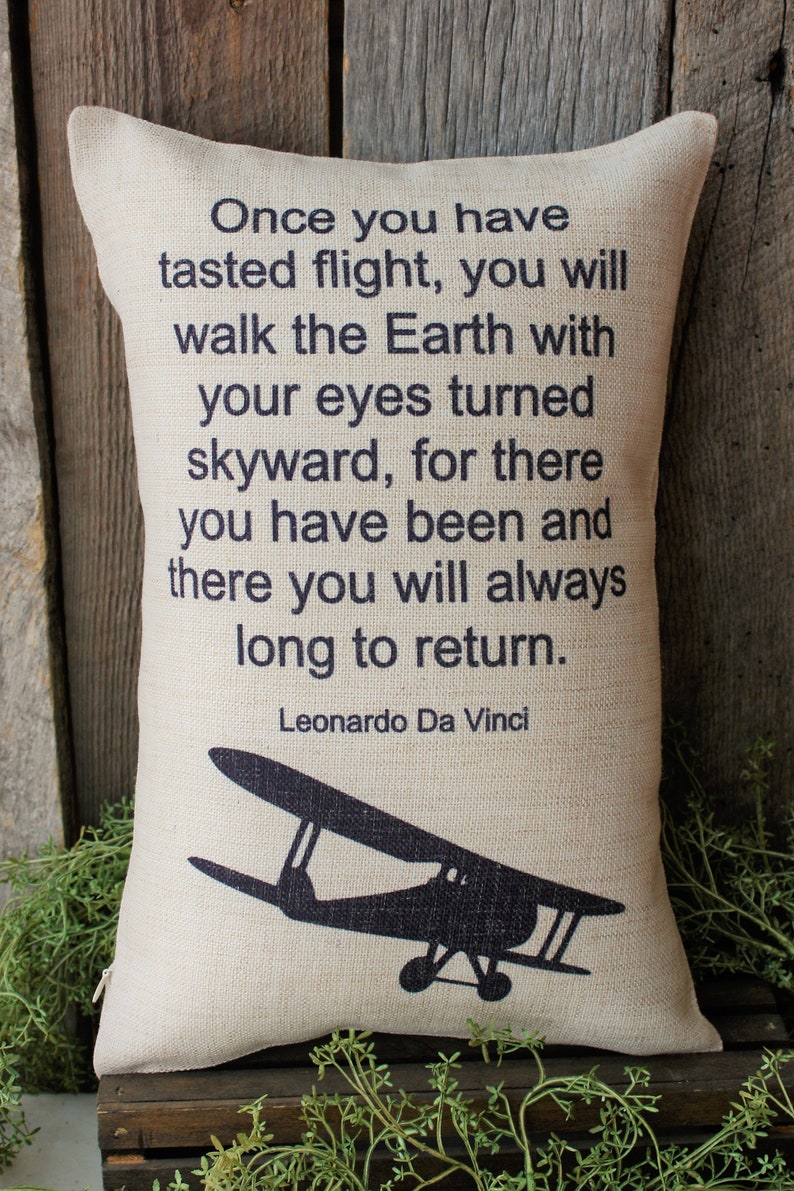 May include: A beige throw pillow with a black silhouette of a vintage airplane and a quote by Leonardo Da Vinci: "Once you have tasted flight, you will walk the Earth with your eyes turned skyward, for there you have been and there you will always long to return."