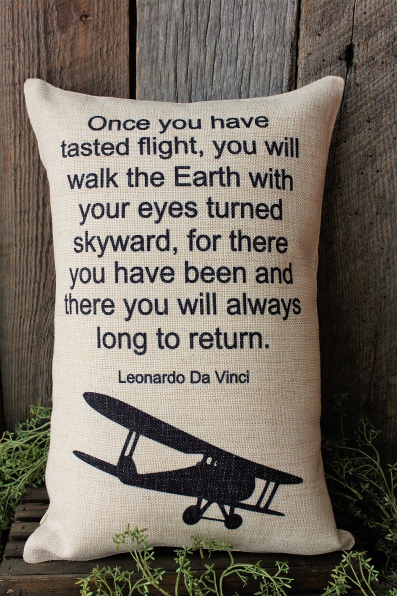 May include: A beige pillow with a black silhouette of a vintage airplane and a quote by Leonardo Da Vinci that reads: "Once you have tasted flight, you will walk the Earth with your eyes turned skyward, for there you have been and there you will always long to return."