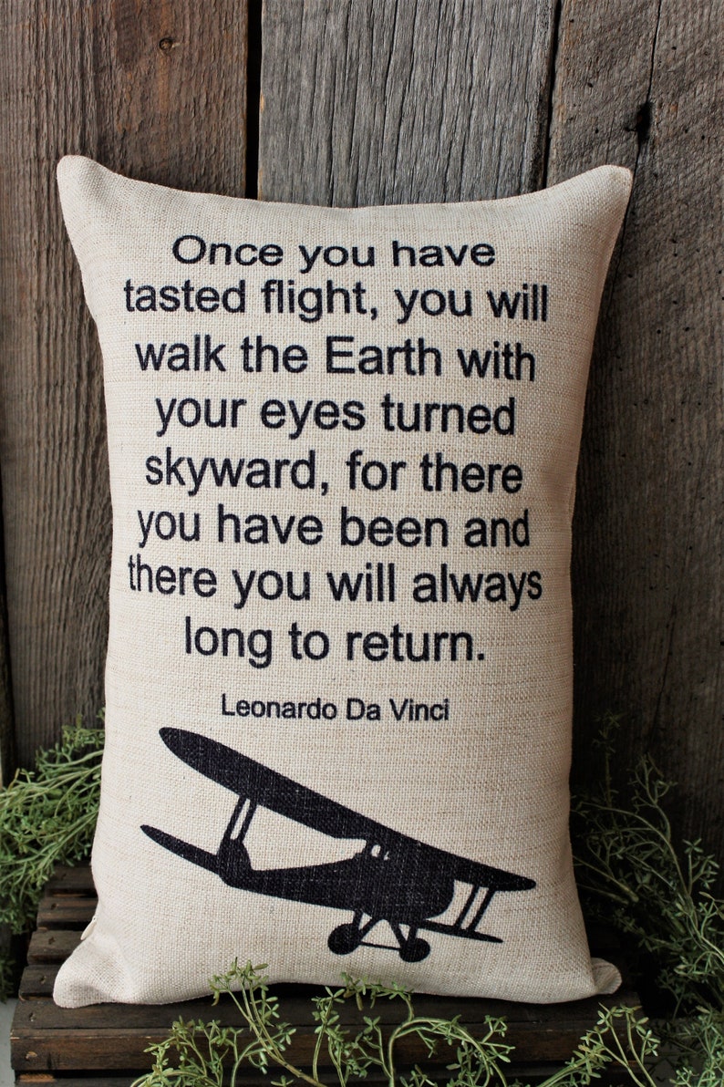 May include: A beige throw pillow with a black silhouette of an airplane and a quote by Leonardo Da Vinci that reads: "Once you have tasted flight, you will walk the Earth with your eyes turned skyward, for there you have been and there you will always long to return."