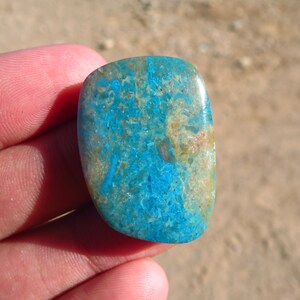 May include: A smooth, polished, blue and brown gemstone with a unique pattern. The stone is oval-shaped and has a glossy finish.