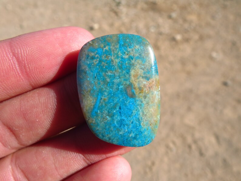 May include: A smooth, polished, blue and brown gemstone with a unique pattern. The stone is oval-shaped and has a glossy finish.