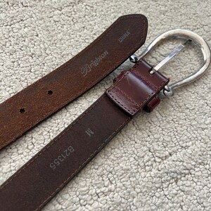 Peut inclure: Une ceinture en cuir marron avec une boucle argent&eacute;e. La ceinture porte la marque "Brighton" et la taille "M". Fabriqu&eacute; en Chine.