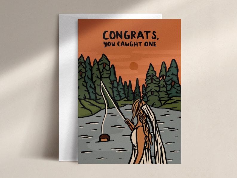 May include: Greeting card with an illustration of a person fishing in a lake, with the text "CONGRATS, YOU CAUGHT ONE." The background features a forest and an orange sky.