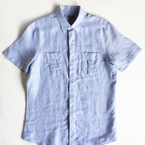 May include: A light blue linen short-sleeved button-down shirt with two flap pockets on the front.