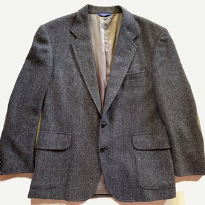 May include: A gray herringbone blazer with two button closures and two flap pockets.
