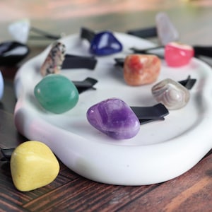 May include: Assortment of colorful gemstone car air fresheners. Each stone is attached to a black clip. The stones include amethyst, green aventurine, yellow jasper, agate, and rose quartz.