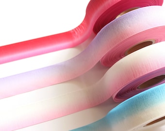 May include: Four rolls of ombre ribbon in pink, purple, white, and blue. The ribbon is made of a soft, textured material and is perfect for adding a touch of color and elegance to any project.