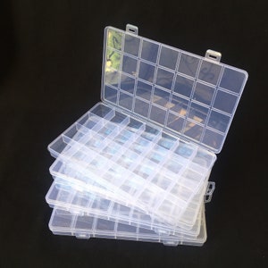 May include: A set of three clear plastic storage boxes with multiple compartments. The boxes are stacked on top of each other, with the top box open.